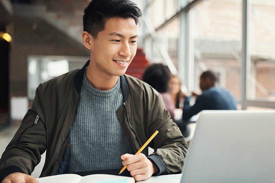 学生在一个开放的地方用笔记本电脑学习在线商业学位.